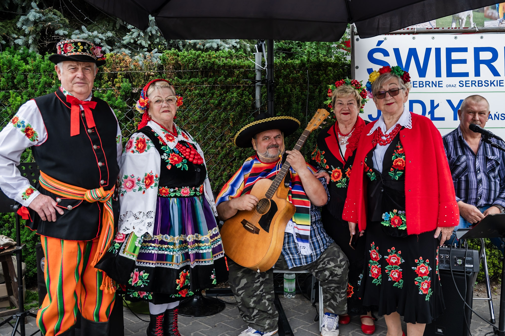 Zespół w strojach ludowych i gitarzysta podczas wydarzenia w Szkółce Ogrodniczej Danika w Żyrardowie.
