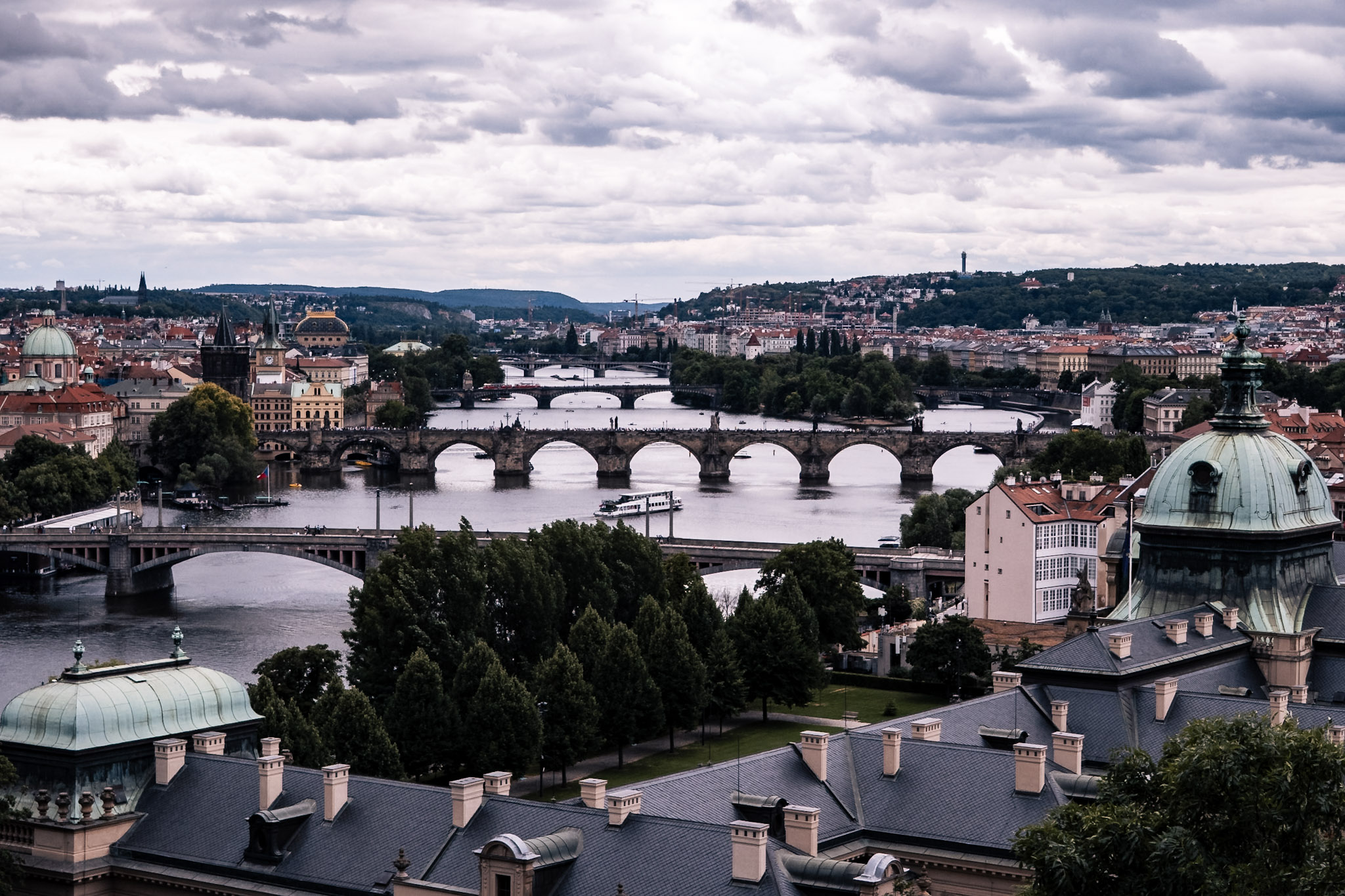 Widok na mosty nad Wełtawą i panoramę Pragi z czerwonymi dachami i zabytkami